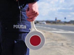 na zdjęciu policjant, trzymający tarczę do zatrzymywania pojazdów