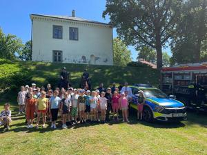 Uczestnicy pikniku przy radiowozie z policjantami na koniach.