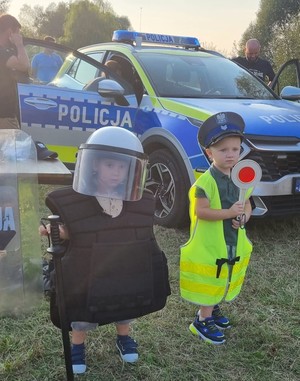 Dzieci przymierzające części umundurowania policyjnego.