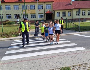 Policjanci wraz z dziećmi na przejściu dla pieszych.