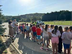 Policjanci wraz z grupą dzieci przy drodze publicznej.