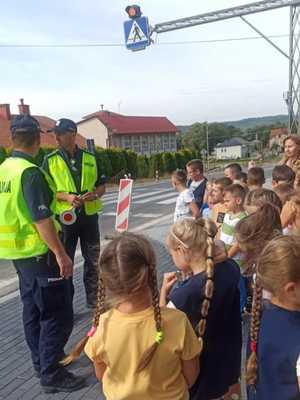 Policjanci wraz z dziećmi przy przejściu dla pieszych.