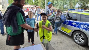 Uczestnik pikniku przymierzający policyjną czapkę oraz kamizelkę odblaskową z napisem POLICJA