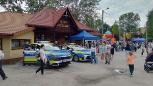 Policyjne radiowozy udostępnione dla uczestników pikniku stojące obok wystawionego stoiska policyjnego.