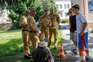 Uczniowie podczas wykonywania zadania zorganizowanego przez strażaków. Dwóch chłopców przenosi manekina.
